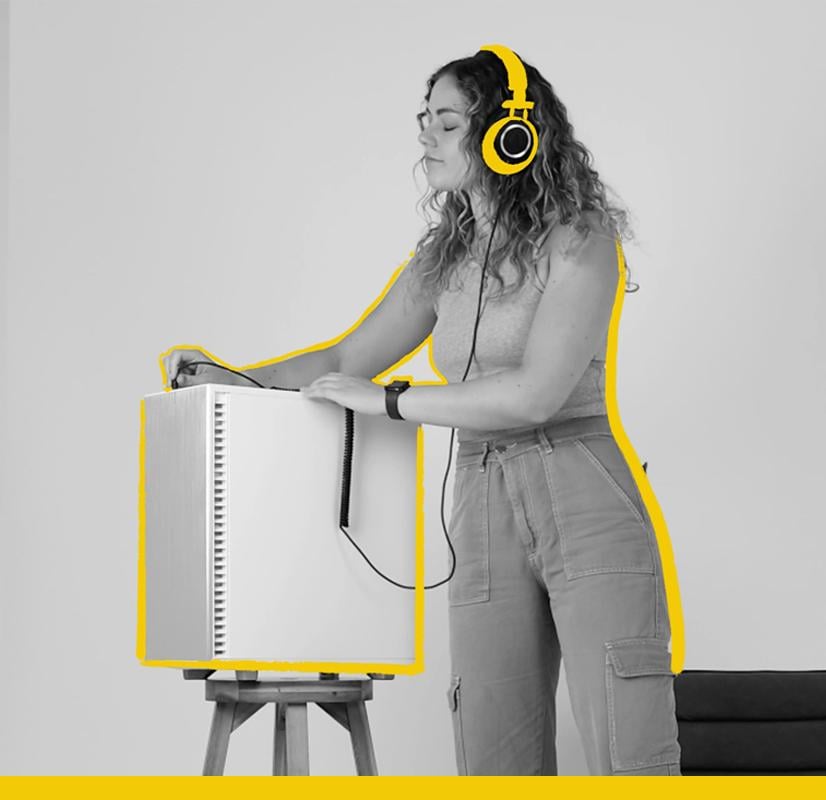 A music producer wearing bright yellow headphones, interacting with a Chillblast Spark Video Ultra Workstation placed on a wooden stand, accented with bold yellow highlights, symbolizing creativity and professional audio production.