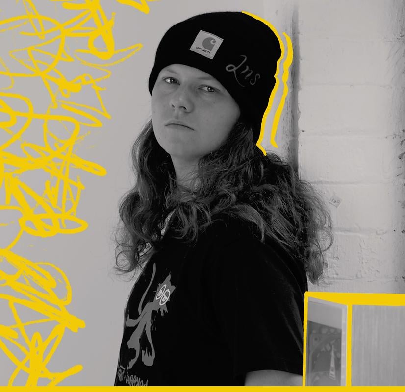 Portrait of a video editor wearing a black beanie and casual attire, set against a background with yellow graffiti-style accents, representing the creative professionals who use the Chillblast Spark Creator PC range.