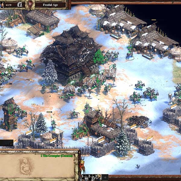 In-game screenshot from Age of Empires II: Definitive Edition showing a snowy village scene during the Feudal Age, with military units and villagers gathering around traditional wooden buildings.