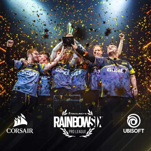 Rainbow Six Siege Pro League team celebrating on stage with confetti falling as they lift the championship trophy, featuring Corsair and Ubisoft logos at the bottom.